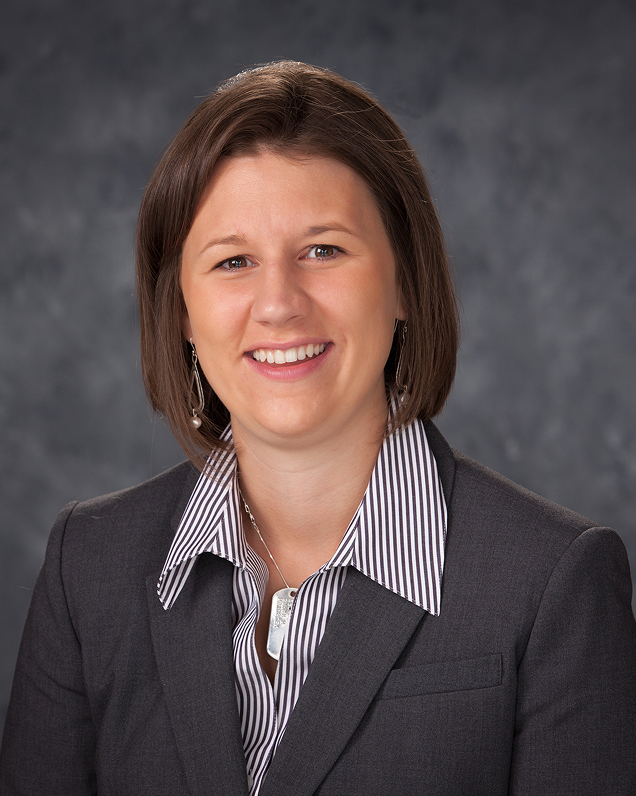 Woman in gray blazer and striped shirt smiling for a professional headshot