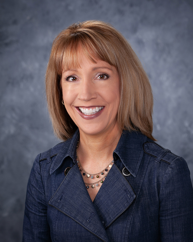 Woman in blue jacket smiling for a professional headshot
