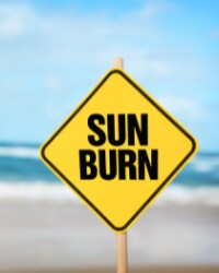 Yellow sign on beach that reads "Sun Burn" 