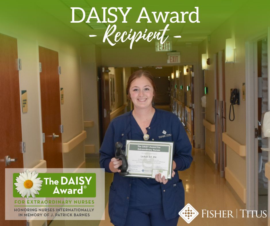 LeAnn Erf poses with DAISY Award in hall of Fisher-Titus, with logos displayed on the image