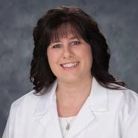 Female healthcare provider in a white lab coat smiling professionally