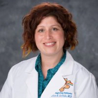 Smiling provider with curly red hair in a white lab coat