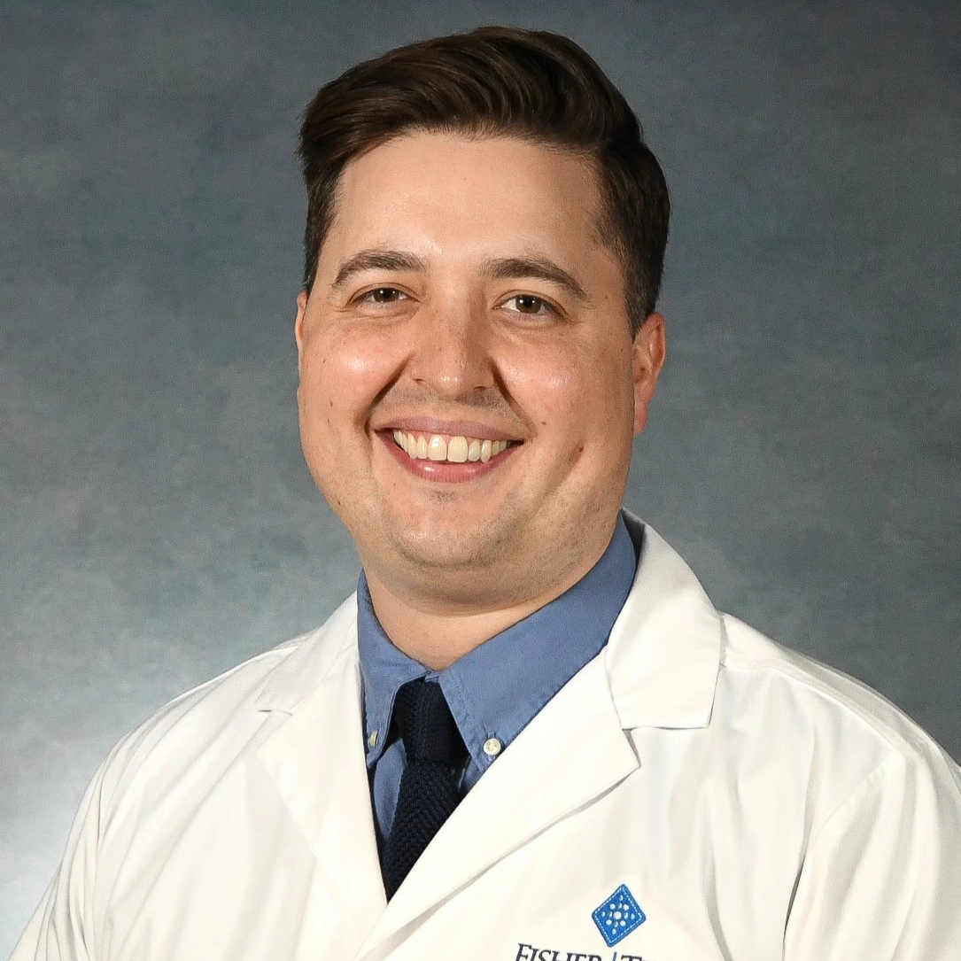 Smiling Fisher-Titus physician in white lab coat and blue shirt with tie