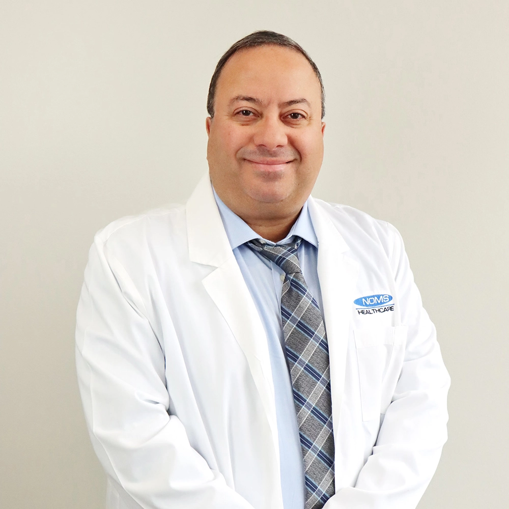 NOMS Healthcare physician in white coat and tie smiling for a professional portrait